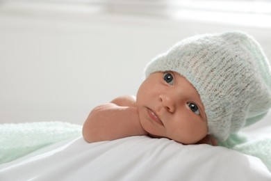 Photo of Adorable newborn baby in hat on bed indoors, space for text