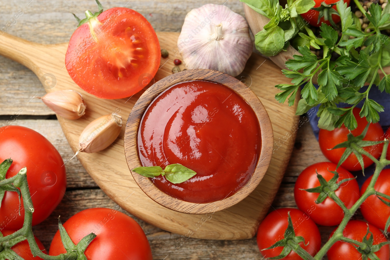 Photo of Tasty ketchup, fresh tomatoes, parsley and spices on wooden table, flat lay