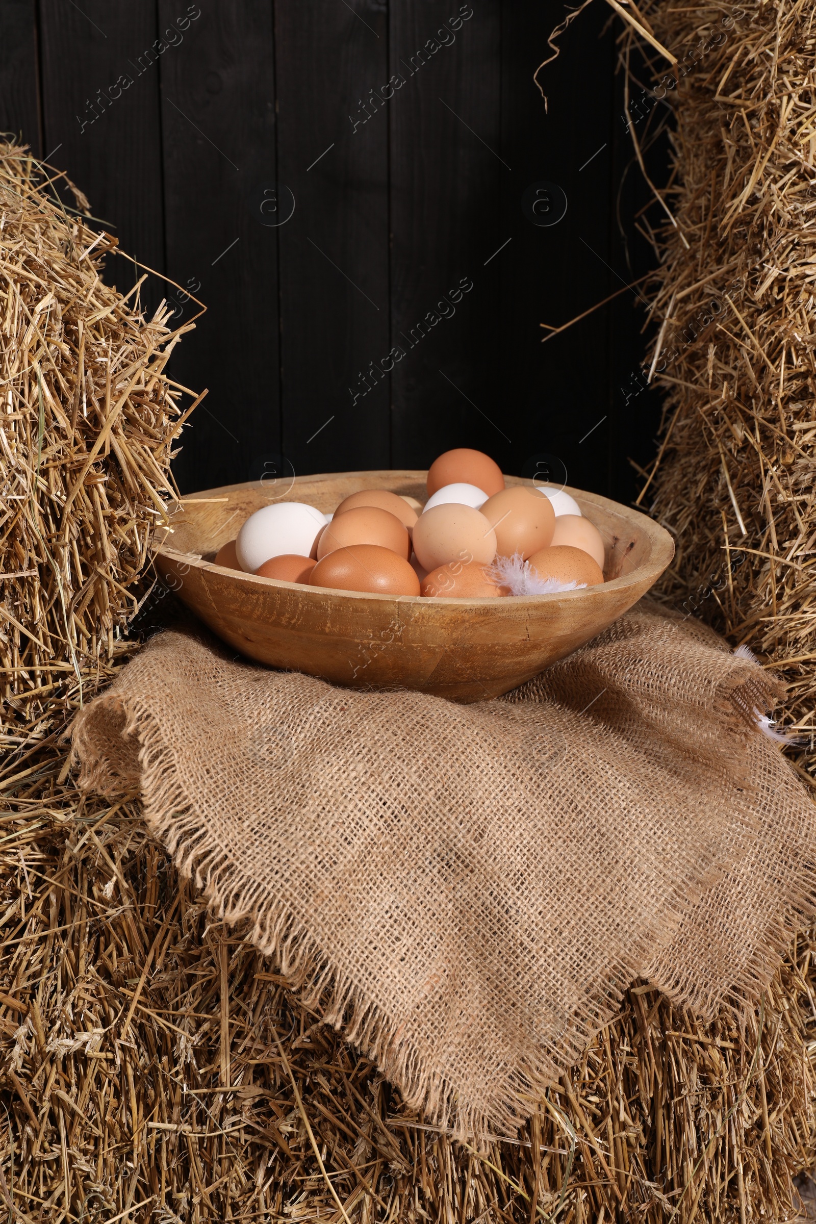 Photo of Fresh chicken eggs in bowl on dried straw bale