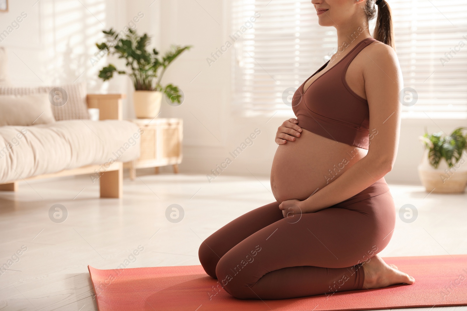 Photo of Young pregnant woman practicing yoga at home, closeup. Space for text