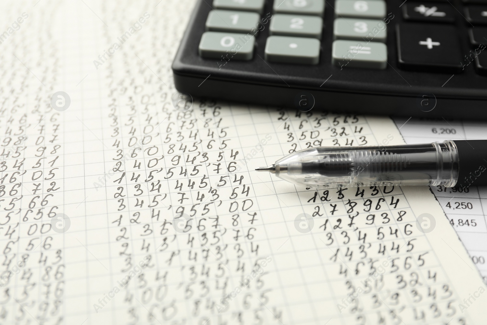 Photo of Calculator and pen on documents with data, closeup