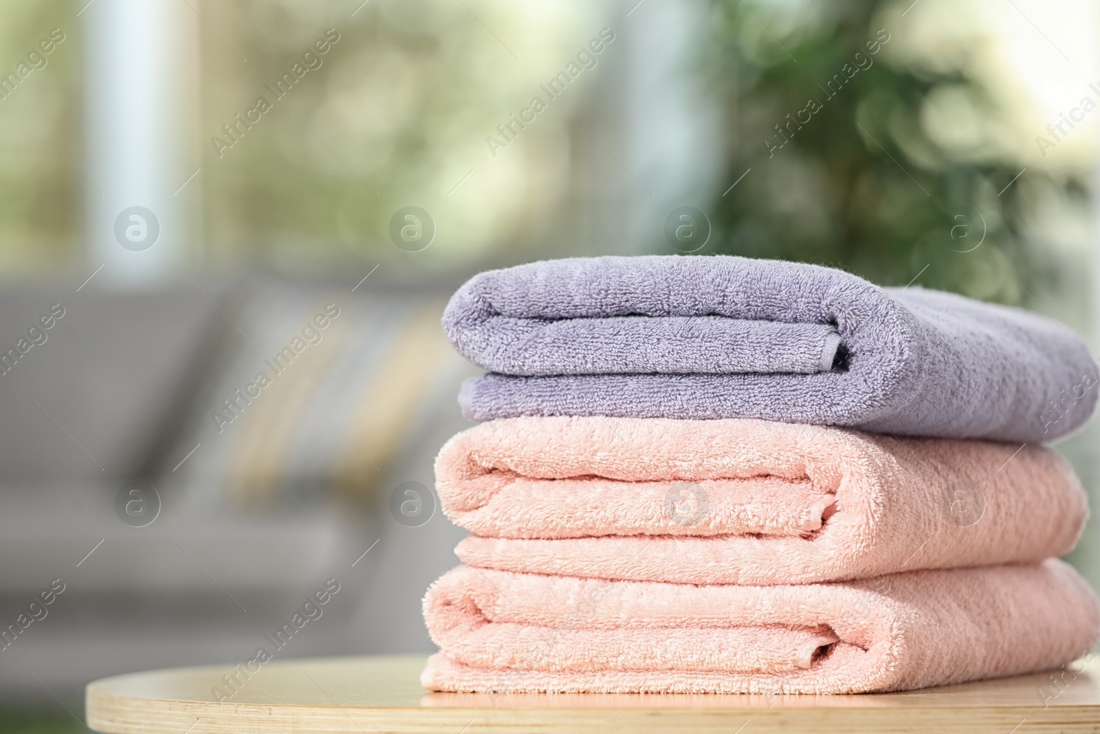 Photo of Stack of folded clean soft towels on table indoors. Space for text