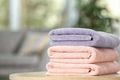 Stack of folded clean soft towels on table indoors. Space for text