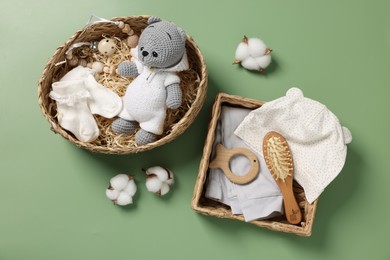 Photo of Different baby accessories, clothes and cotton flowers on green background, flat lay