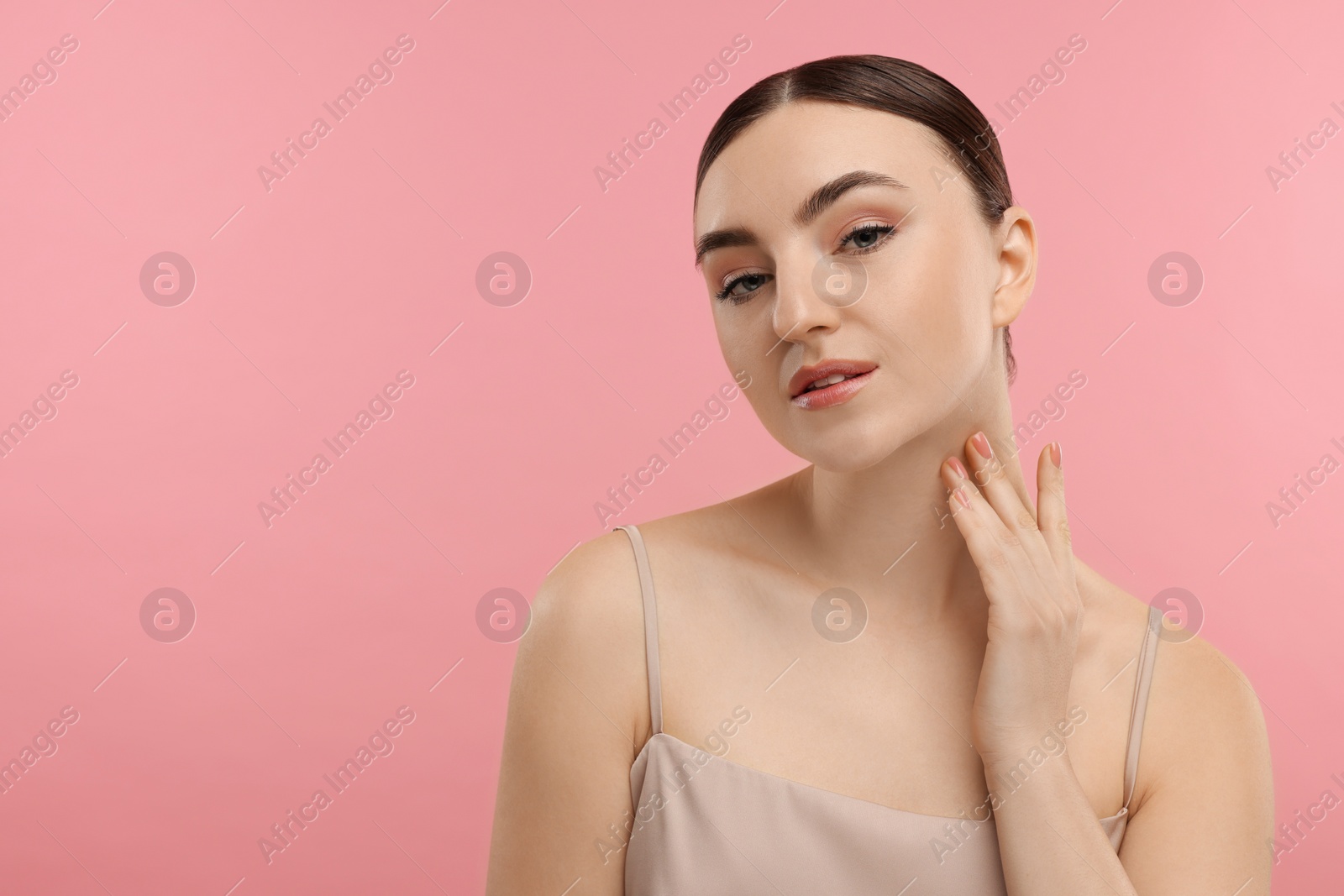 Photo of Beautiful woman touching her neck on pink background. Space for text