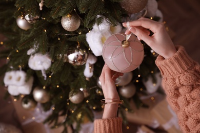 Photo of Woman decorating Christmas tree at home, top view