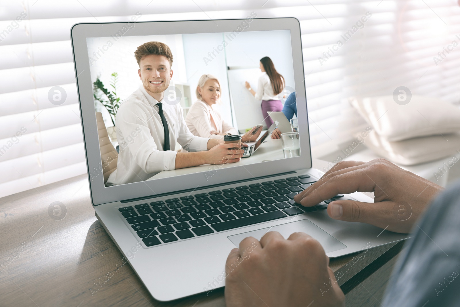 Image of Man attending online video conference via modern laptop at table, closeup