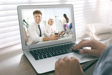 Man attending online video conference via modern laptop at table, closeup