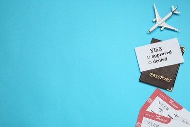 Flat lay composition with passport, toy plane and tickets on light blue background, space for text. Visa receiving
