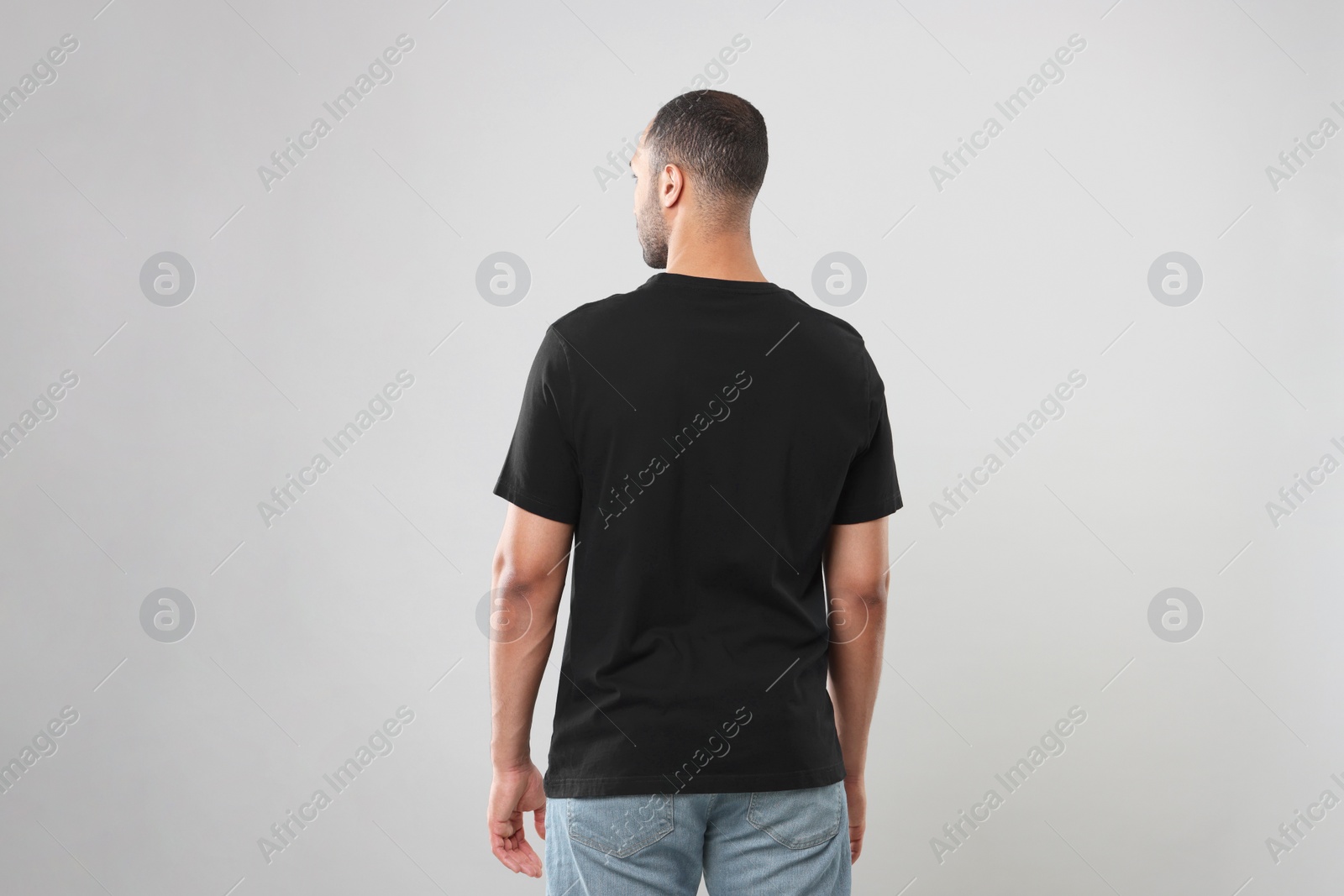 Photo of Man wearing black t-shirt on gray background, back view