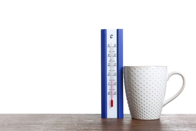 Photo of Thermometer and cup of hot tea on wooden table against white background. Space for text