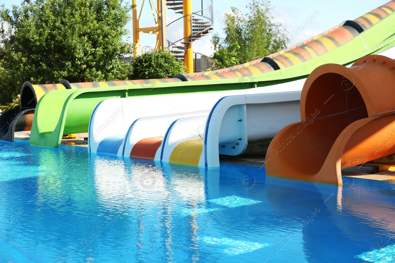 Photo of Different colorful slides and swimming pool in water park on sunny day