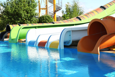 Photo of Different colorful slides and swimming pool in water park on sunny day