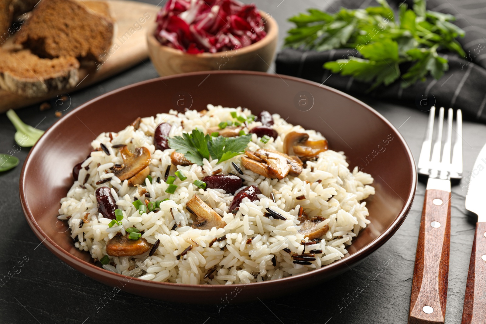 Photo of Delicious rice pilaf with mushrooms on black table