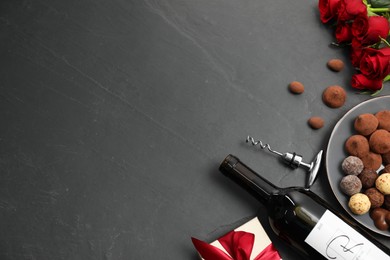 Photo of Red wine, chocolate truffles, gift box, roses and corkscrew on gray table, flat lay. Space for text