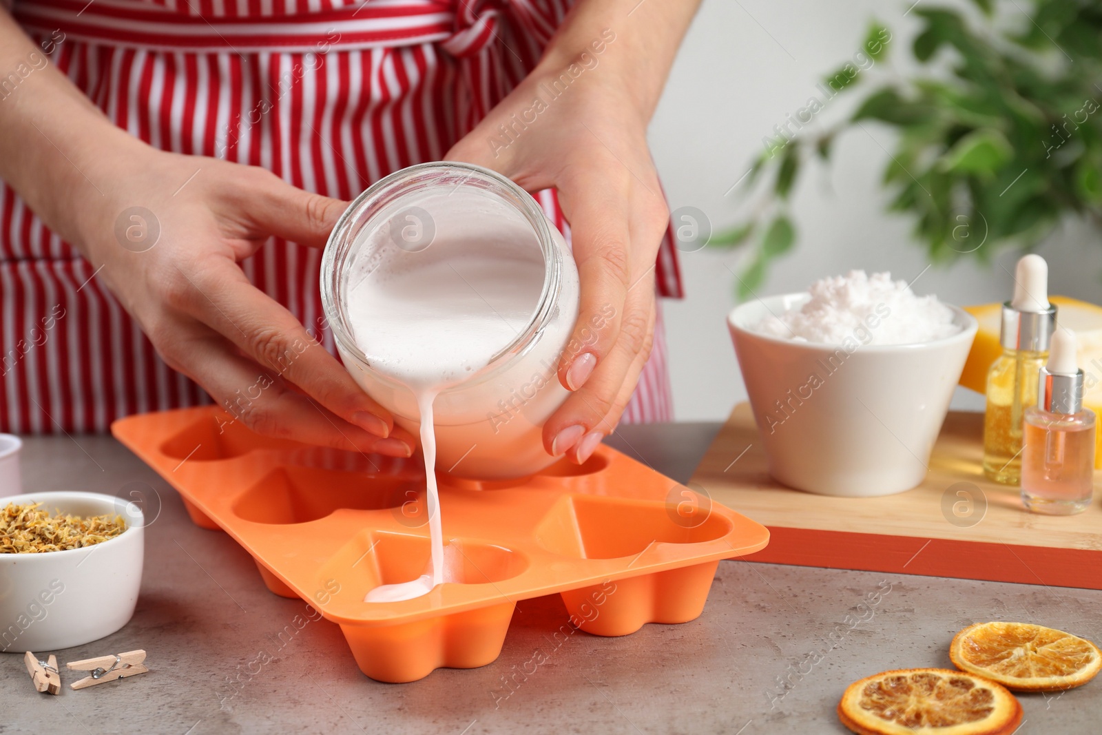 Photo of Woman making natural handmade soap at grey stone table, closeup