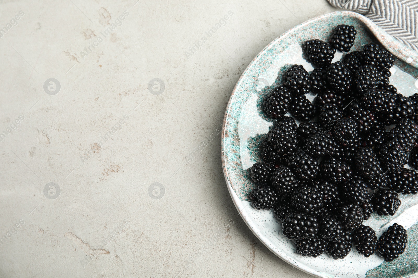 Photo of Plate of tasty ripe blackberries on light table, flat lay with space for text