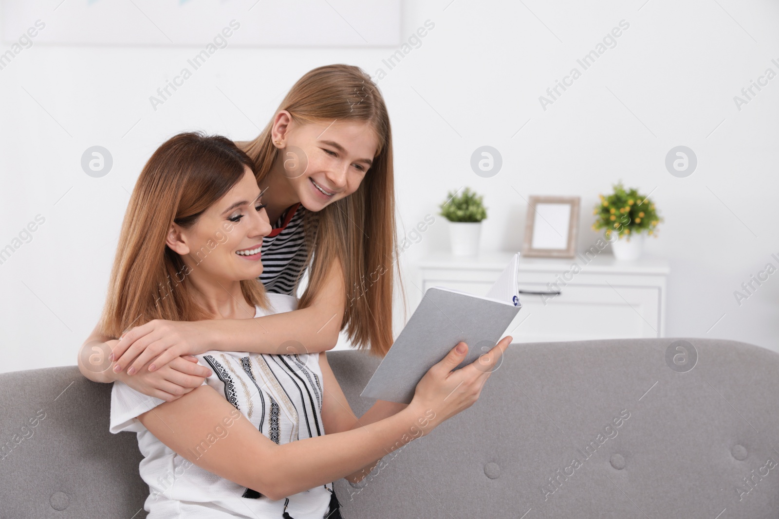 Photo of Happy mother and her teenage daughter with book at home