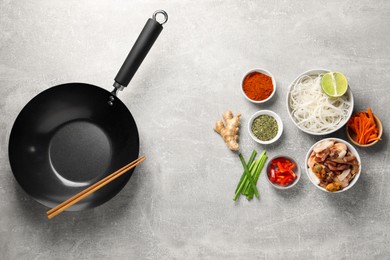 Photo of Flat lay composition with black wok, spices and products on grey textured table