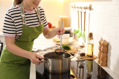 Woman making bouillon on stove in kitchen, closeup. Homemade recipe