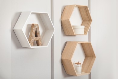 Honeycomb shaped shelves with decorative elements on white wall