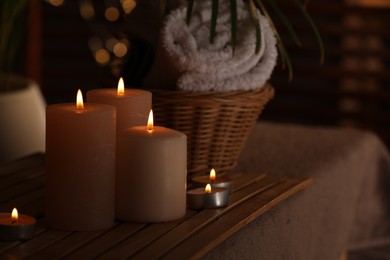 Spa composition with burning candles on massage table in wellness canter, space for text