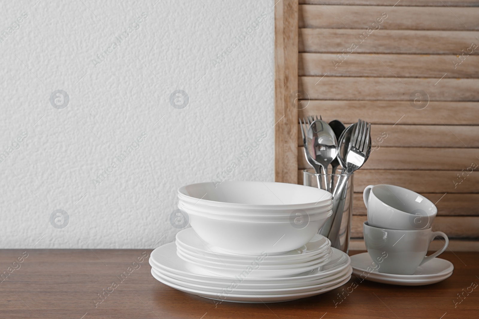 Photo of Set of clean dishes and cutlery on table in kitchen