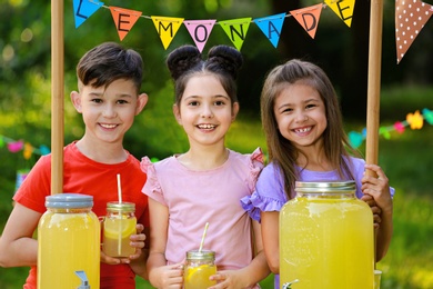 Cute little children at lemonade stand in park. Summer refreshing natural drink