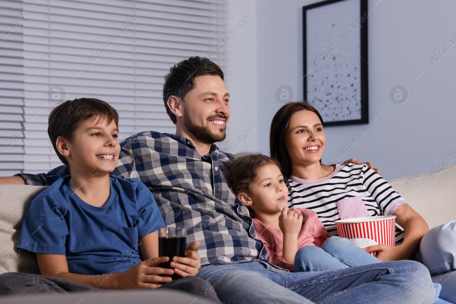 Photo of Happy family watching TV at home in evening