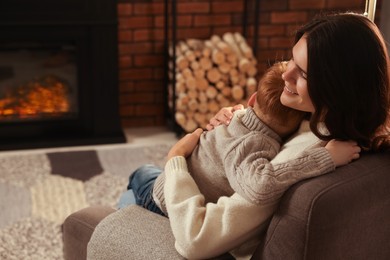 Photo of Happy mother and son hugging near fireplace at home