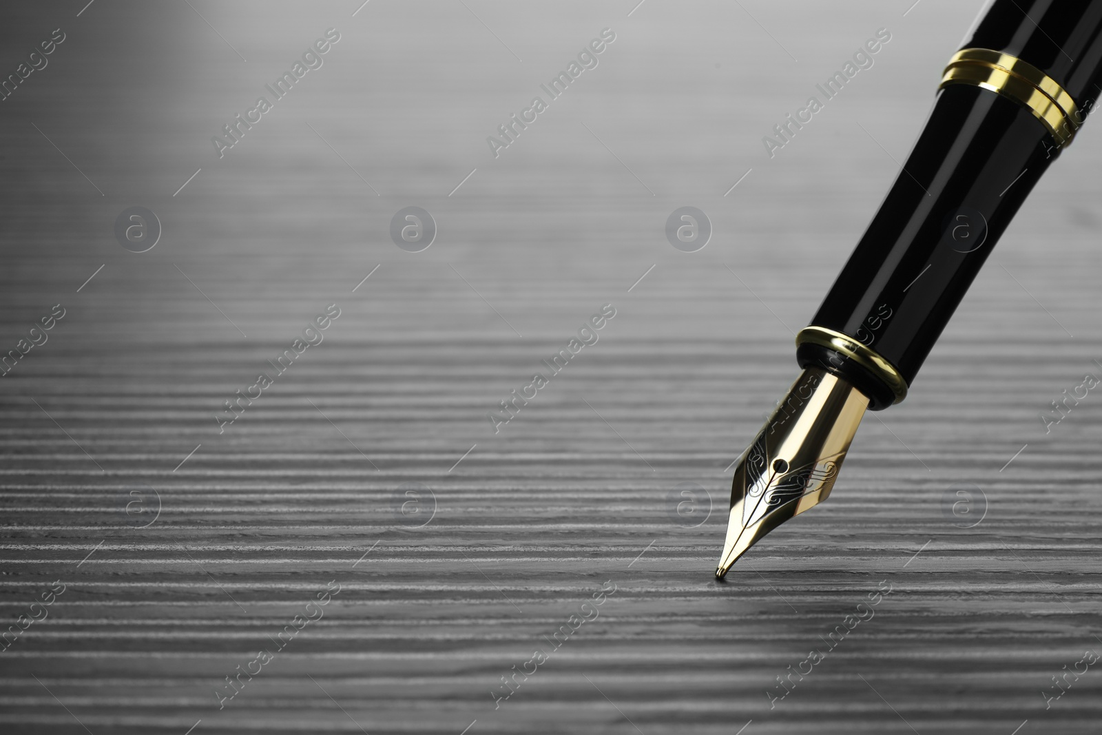 Photo of Stylish fountain pen on black wooden table, closeup. Space for text