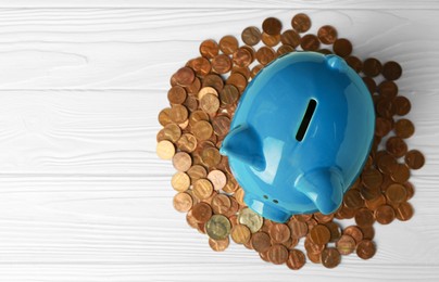 Photo of Ceramic piggy bank and coins on white wooden table, flat lay. Space for text