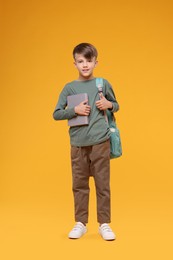 Cute schoolboy with book on orange background