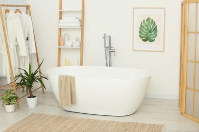 Photo of Stylish bathroom interior with beautiful tub and houseplants