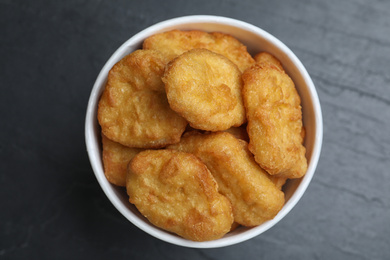 Photo of Bucket with tasty chicken nuggets on black table, top view