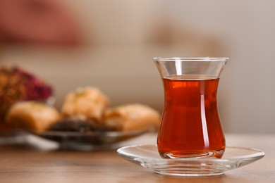 Glass with tasty Turkish tea on wooden table indoors, space for text