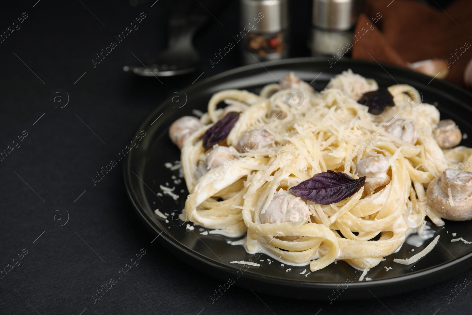 Photo of Delicious pasta with mushrooms on black table, closeup