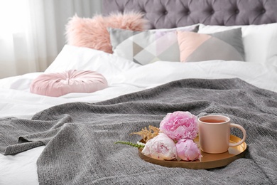 Photo of Cup of drink and bouquet on bed with pillows in room