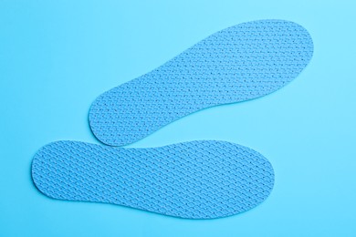 Photo of Pair of breathable shoe insoles on light blue background, flat lay