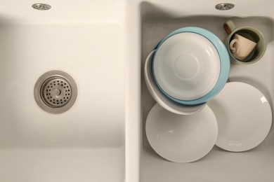 Photo of Clean tableware in white sink, top view