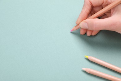 Photo of Woman drawing on color paper with pastel pencil, closeup. Space for text