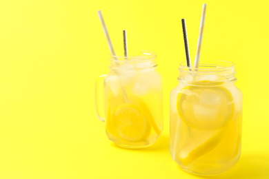 Photo of Natural lemonade on yellow background, space for text. Summer refreshing drink