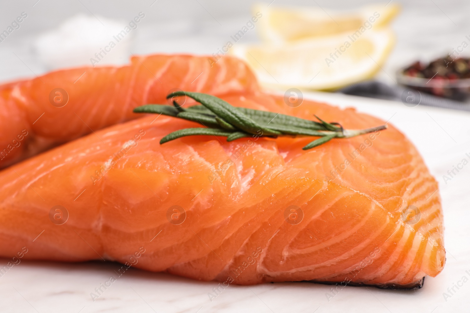 Photo of Marble board with tasty salmon fillet on table, closeup