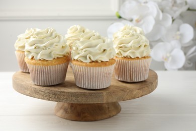 Photo of Tasty vanilla cupcakes with cream on white wooden table