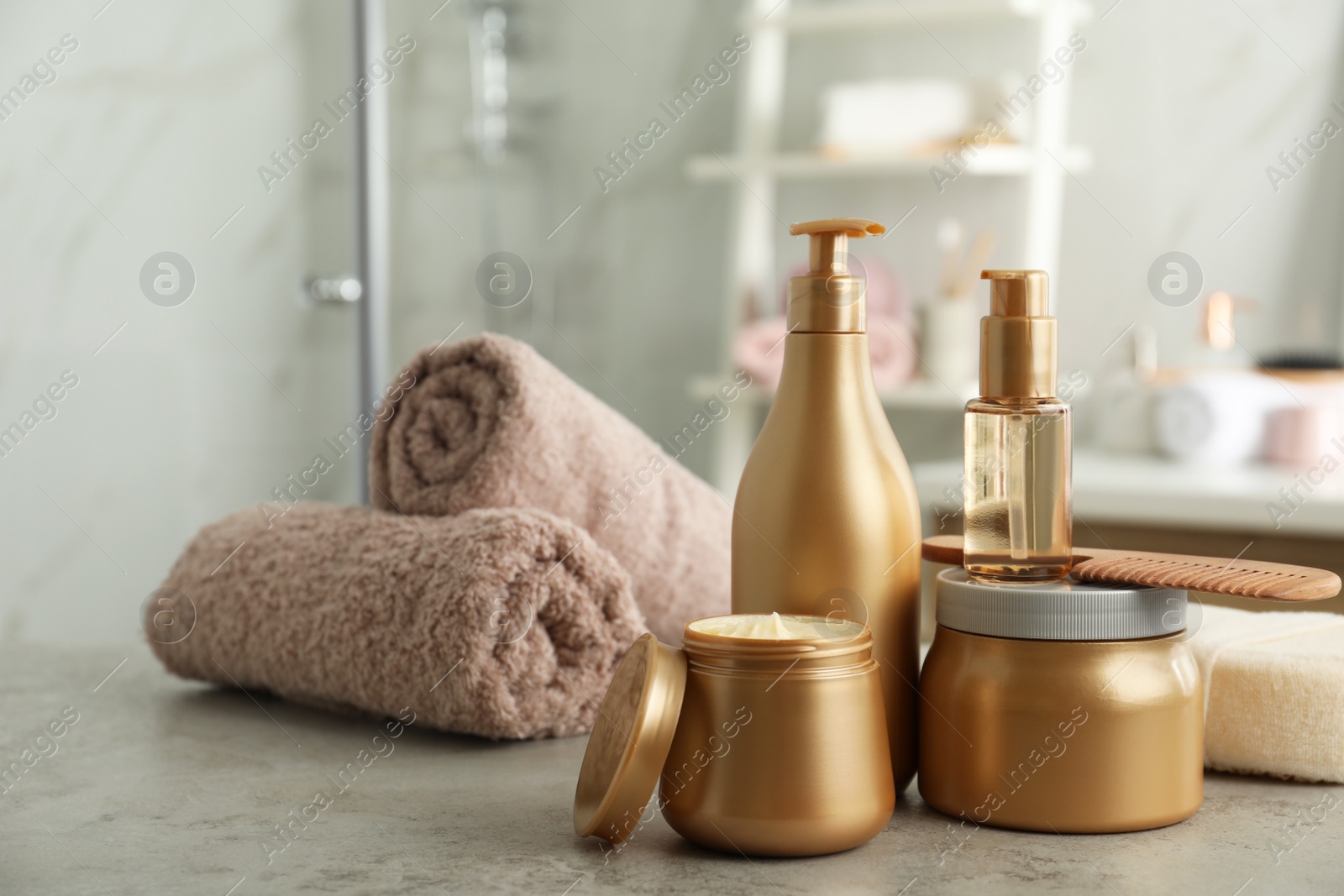 Photo of Different hair care products, towels and comb on table in bathroom