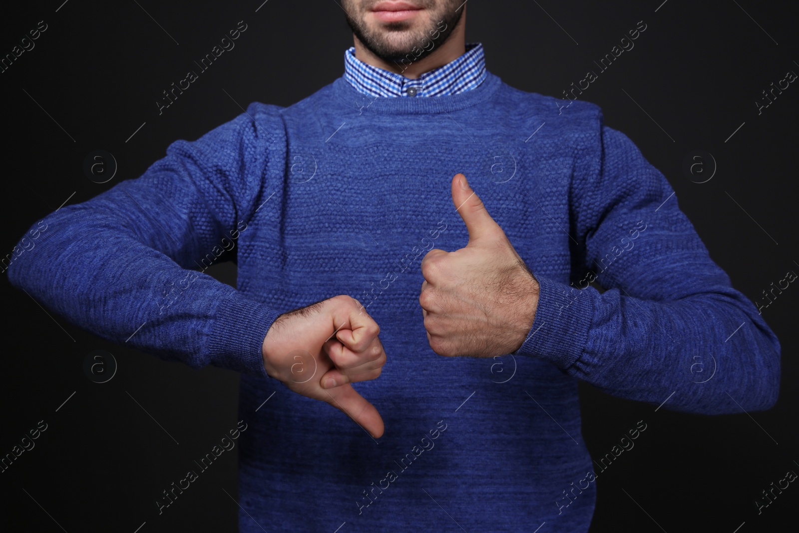 Photo of Man showing THUMB UP and DOWN gesture in sign language on black background, closeup