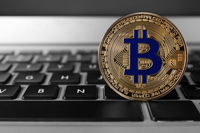 Photo of Golden bitcoin on computer keyboard, space for text. Digital currency