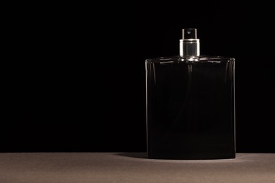 Luxury men`s perfume in bottle on grey table against black background, space for text