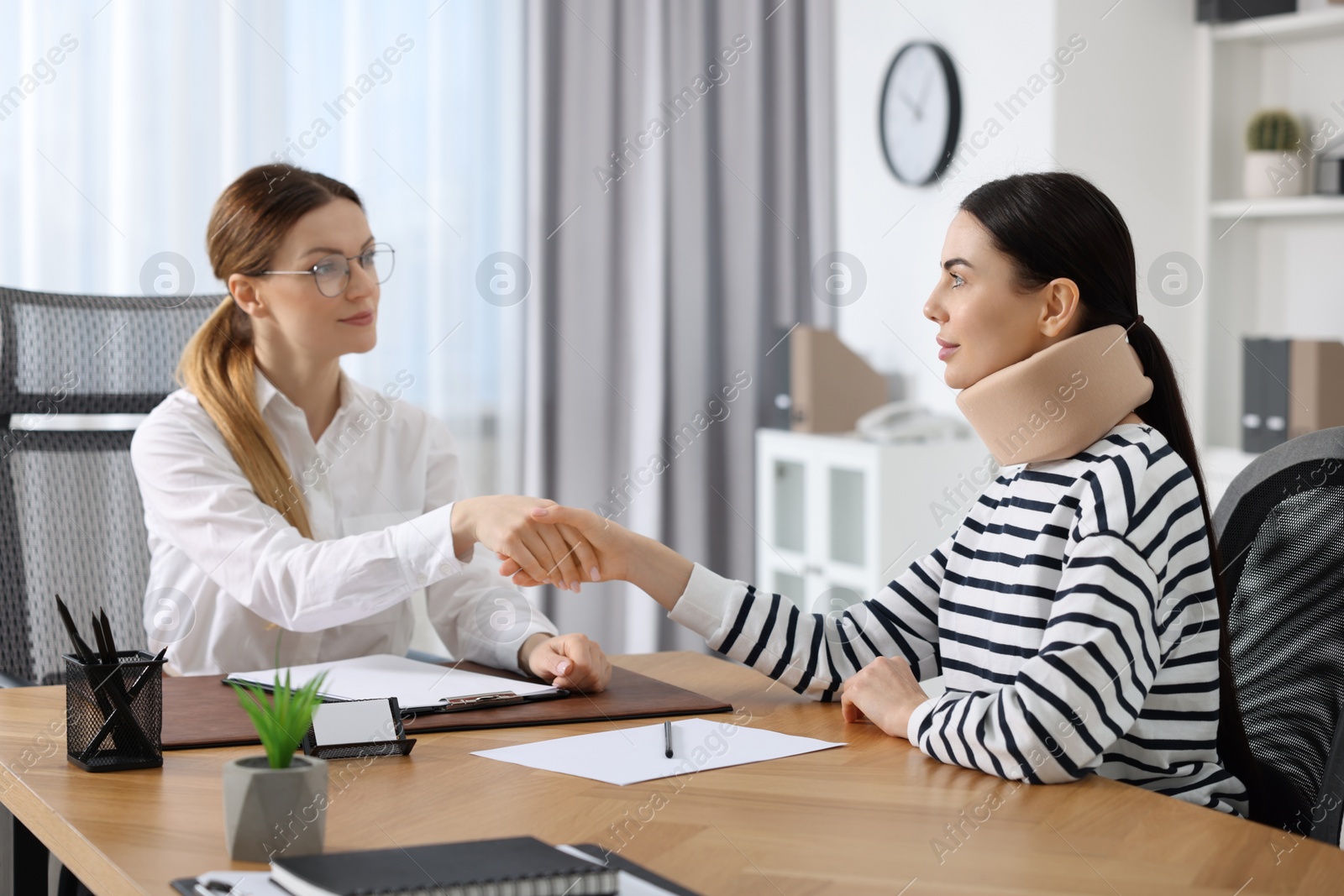 Photo of Lawyer shaking hands with injured client in office