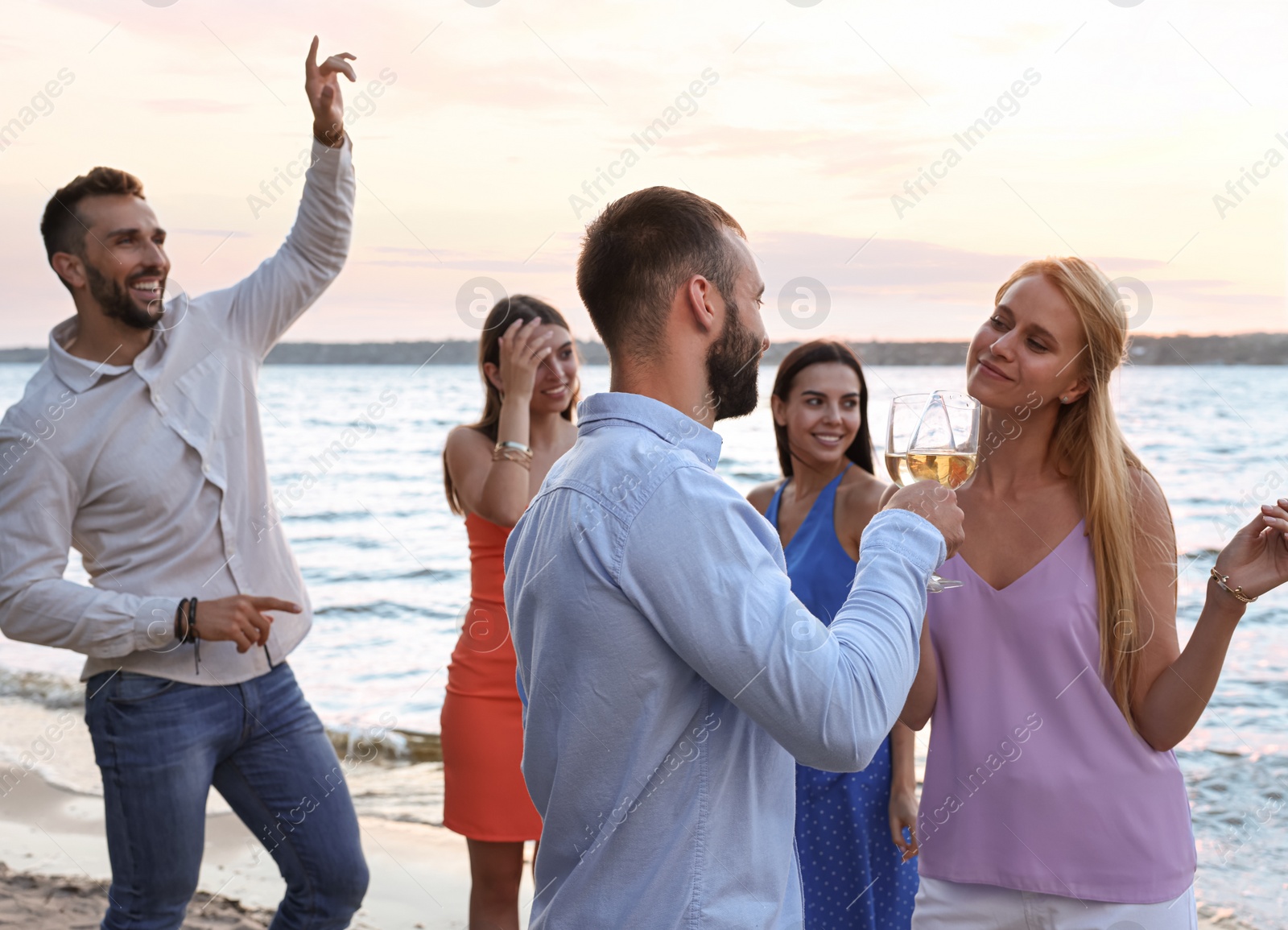 Photo of Friends with glasses of wine having fun near river at summer party